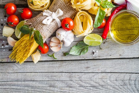 Pasta and ingredients tomato, garlic, onion, oil, basil  on rustic backgroundの写真素材