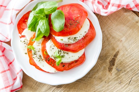 Caprese salad on white plate, wood background, closeupの写真素材