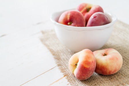 Peaches in white bowl, white wood background, copy spceの写真素材