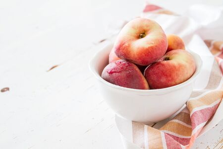 Peaches in white bowl, white wood background, copy spceの写真素材