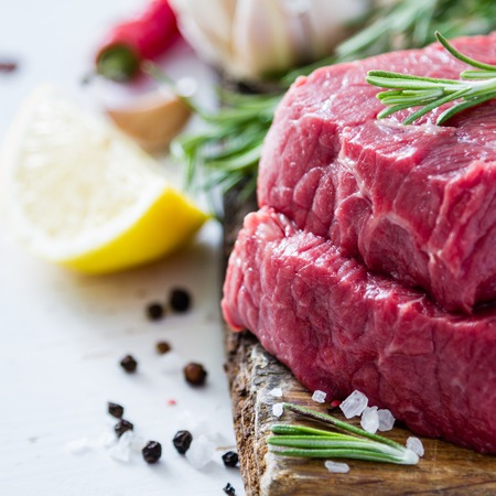 Raw sliced meat rosemary on wood backgroundの写真素材