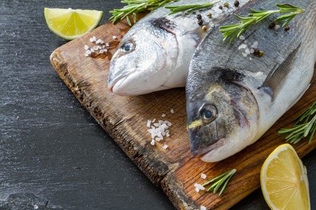 Raw fish and ingredients on dark stone backgroundの写真素材