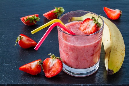 Banana strawberry smoothie ingredients dark stone backgroundの写真素材