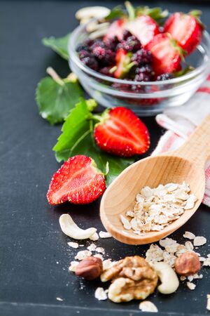 Breakfast - oatmeal with honey and berries, blue bowl, dark backgroundの写真素材
