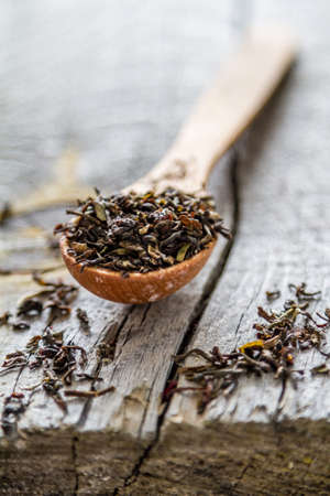 Dry black tea in wood spoon, white wood backgroundの写真素材