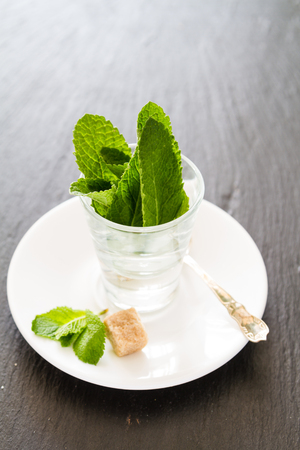 Mint in glass cups, chocolate, nuts, dark stone backgroundの写真素材