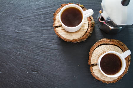 Coffee in white cups on wood boards dark stone backgroundの写真素材