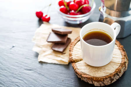 Coffee in white cups on wood boards, chocolate, berries dark stone backgroundの写真素材