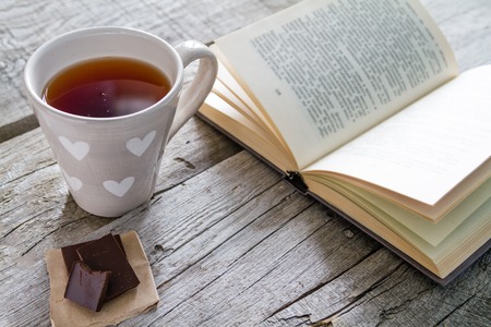 Lifestyle - tea chocolate and book, rustic wood backgroundの写真素材
