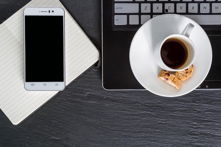 Business breakfast - coffee cookies and notepad, dark stone background