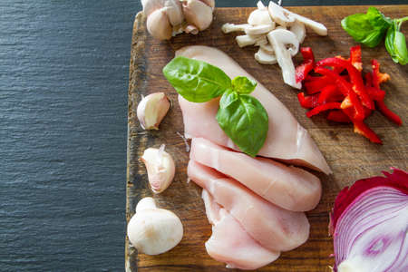 Chicken breast and ingredients on dark stone background, copy space, top viewの写真素材