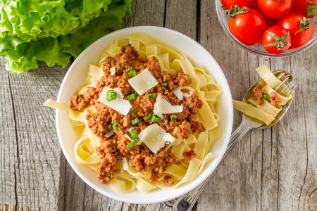 Spaghetti bolognese with salad and tomatoes, rustic wood background, top viewの写真素材