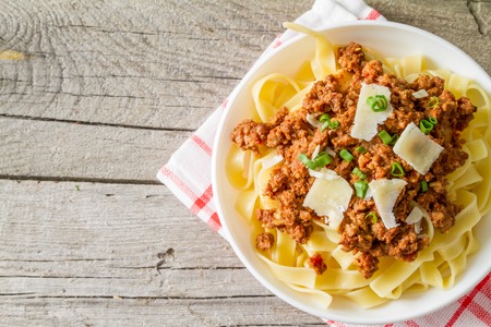 Spaghetti bolognese with salad and tomatoes, rustic wood background, top viewの写真素材