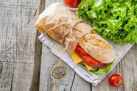 Sandwich with cheese abd ham, salad and tomatoes, rustic wood background