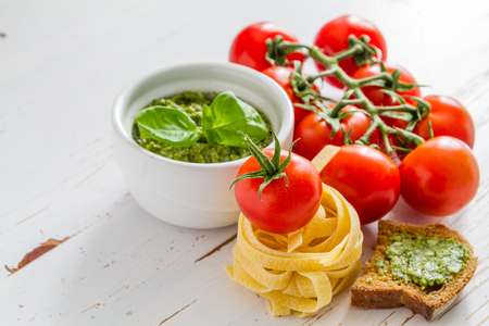 Pesto sauce pasta and tomatoes, white wood background, copy spaceの写真素材