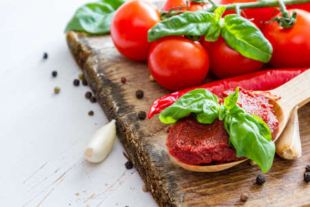 Tomato sauce and ingredients on white wood background, copy space