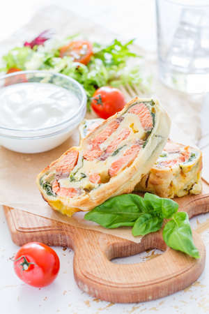 Salmon and spinach strudel on white wood backgroundの写真素材