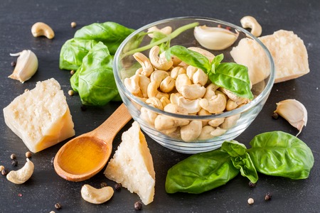 Pesto and ingredients an dark stone background, copy spaceの写真素材