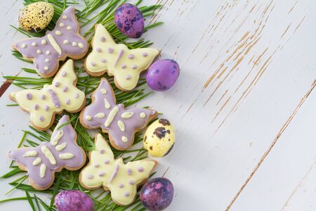 Easter cookies and eggs with grass, white wood background