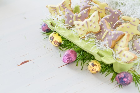 Easter cookies and eggs with grass, white wood background