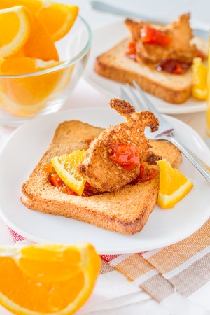 Bunny shaped toast with jam, juice and tea, white wood backgroundの写真素材