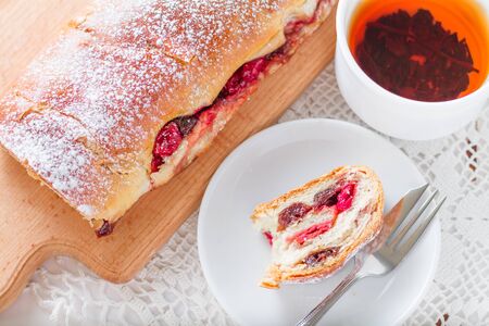 Baked roll with tea, white knitted table cloth, top view