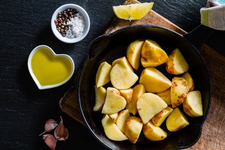 Raw potato slices with herbs, spices, dark stone backgroundの写真素材