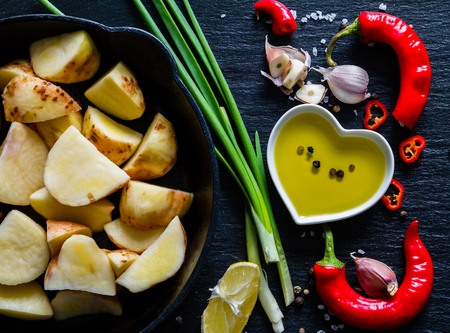 Raw potato slices with herbs, spices, dark stone backgroundの写真素材