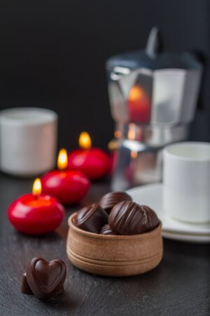 Chocolate candies with coffee and candles, dark stone backgroundの写真素材