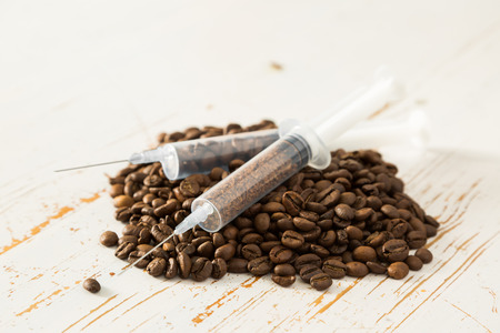 Health care concept - coffee beans in plastic syringe, white background, copy space