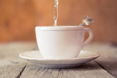 Pouring tea in white cup with tea infuser, copy spaceの写真素材