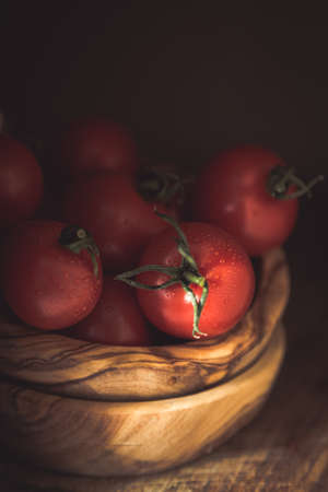 Fresh tomatoes in wood bowl, dark photo, copy spaceの写真素材