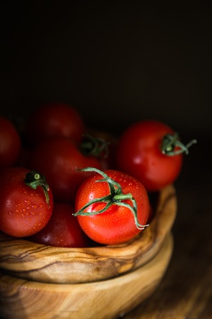 Fresh tomatoes in wood bowl, dark photo, copy spaceの写真素材