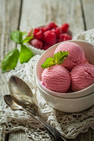 Raspberry ice cream in white bowl, rustic wood background, copy spaceの写真素材