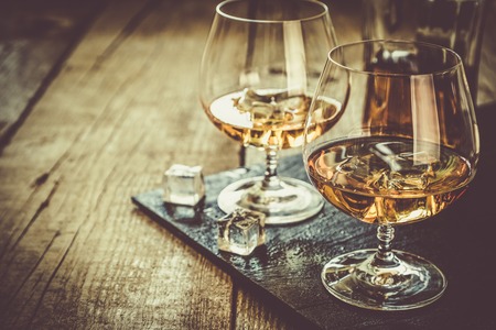 Cognac in glasses on rustic backgrpund, copy space, toned