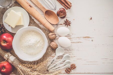 Ingredients for baking - milk, butter, eggs, flour, wheat on white wood background, copy space, tonedの写真素材