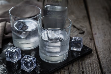 Vodka in shot glasses on rustic wood backgroundcopy space