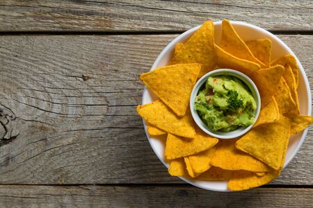 Guacamole sauce and nachos on wood background, copy space