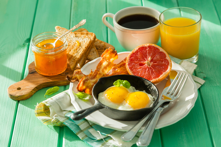 Summer breakfast - eggs, bacon, toast, jam coffee juice copy spaceの写真素材