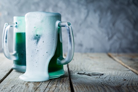 Green beer in mugs on rustic wood backgroundの写真素材