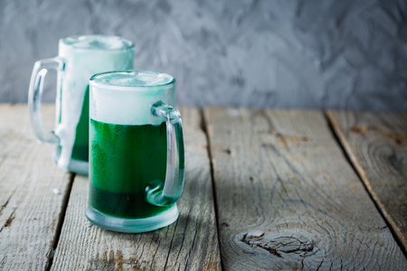 Green beer in mugs on rustic wood backgroundの写真素材