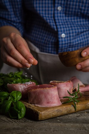 Preparing filet mignon - hands seasoning the steak, wood backgroundの写真素材