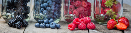 Berries in glass jars - homemade jam, smoothie, low fat dessert, rustic wood backgroundの写真素材