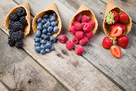 Selection of summer berries in ice cream cones on rustic background. Healthy dessert, lifestyle.の写真素材