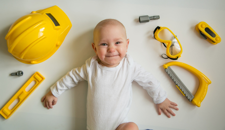 Baby playing with construction tools on white backgroundの写真素材