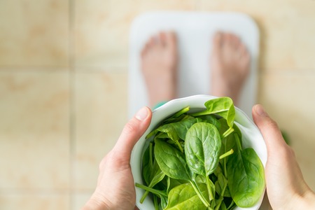 Dieting and excercise concept - female in athlectic clothes eating green saladの写真素材