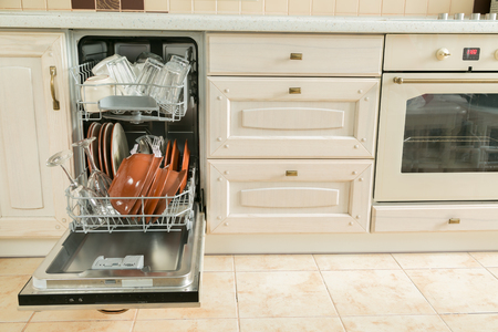 Dishwasher full with clean dishes in kitchen backgroundの写真素材