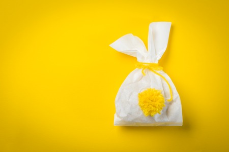 Easter concept - bunny shaped bag with eggs and flowers on bright yellow background,の写真素材