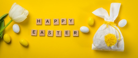 Easter concept - bunny shaped bag with eggs and flowers on bright yellow background,
