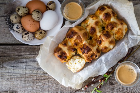 Easter hot cross buns with eggs and milk on rustic wood background, copy space, top view